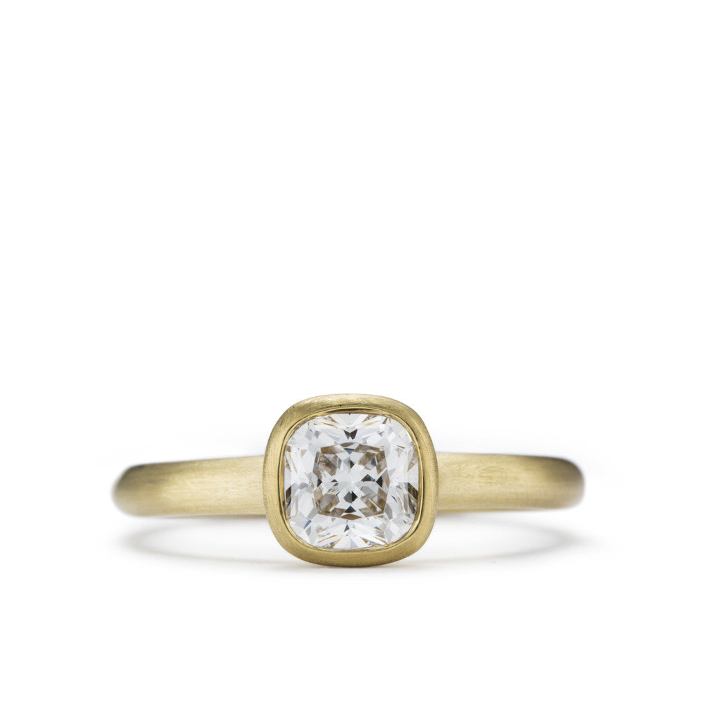 Cushion shaped soft bezel solitaire engagement ring in yellow gold. 